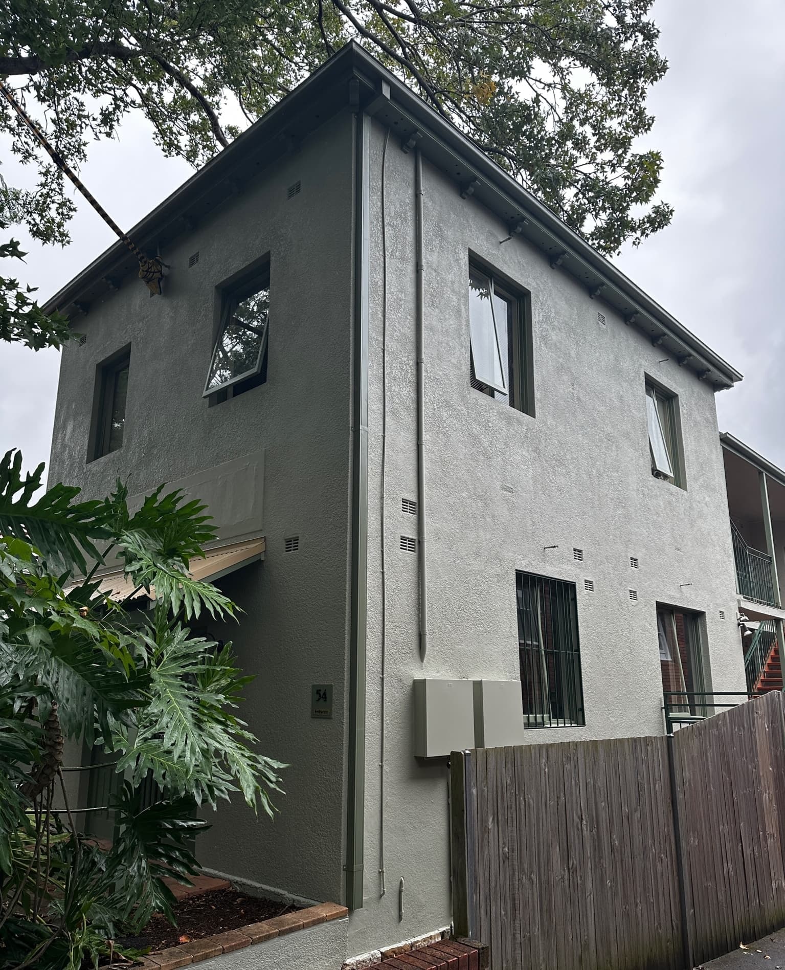 Two-storey rendered home repainted in a dark grey